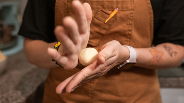 Artisan rolling tortilla dough between palms to form a ball for pressing